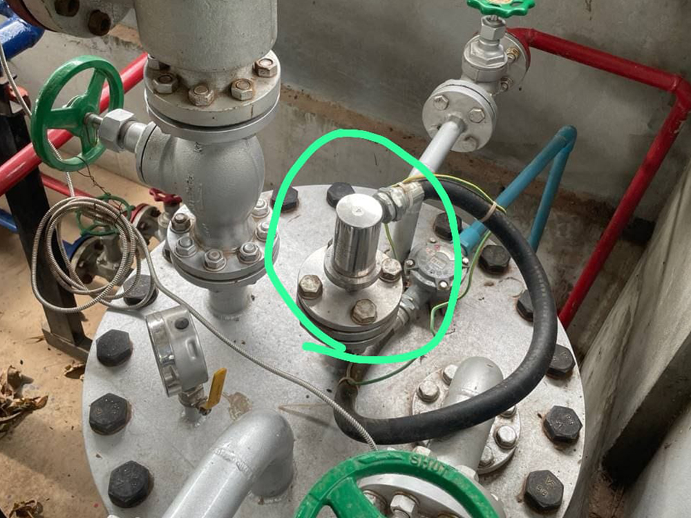 On-site photo showing a magnetostrictive level sensor connected to industrial piping with valves and pressure gauges.